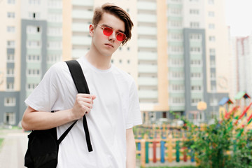 Young man in red glasses with backpack. Street Style outdoor