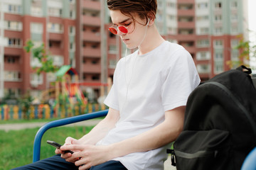 Student sitting and using phone in red glasses. Music listening