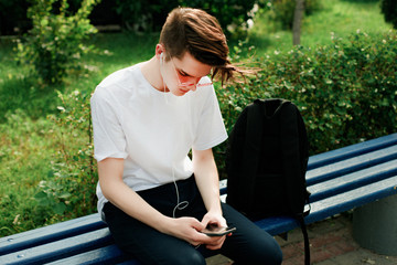 Young man with red glasses listening music with phone in hands