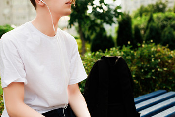Young man with headphones sits in park. Close view
