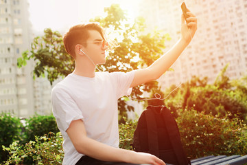 Student taking selfie in park. Sunlight, street style