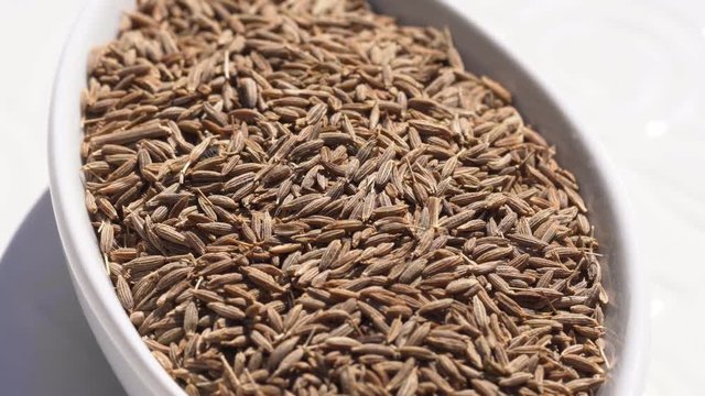 Dry spices cumin seeds on a rotary table. 4K. Macroshooting.