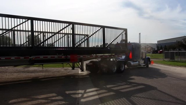 A semi with an oversized load pulls out with an escort behind in slow motion.