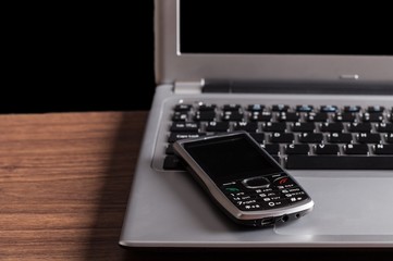 Cell phone sitting on top of a laptop keyboard