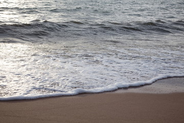 Sand beach with sea waves in the sunset.