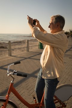 Senior man taking pictures near sea side at promenade