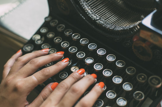 Woman's  hands writing on a vintage typewriter. Young woman writer at home, work on typewriter.