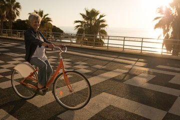Senior woman riding bicycle at promenade