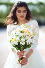 A beautiful bride in a white wedding dress and with a bouquet of flowers enjoying the moment. Wonderful mood, beautiful waves, great atmosphere. wedding concept.