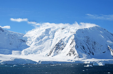 Fototapeta na wymiar Antarctic ocean, Antarctica. Glacier Snow Covered Mountain. Dramatic blue Sky background 