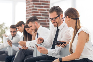 employees of the company using their smartphones sitting in the office lobby