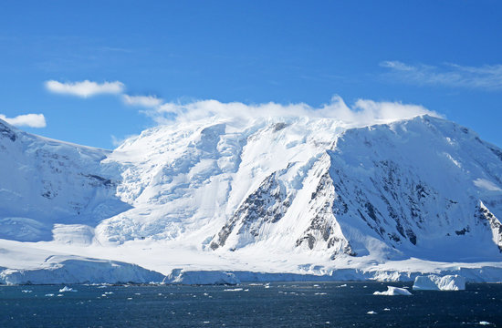 Antarctic ocean, Antarctica. Glacier Snow Covered Mountain. Dramatic blue Sky background
