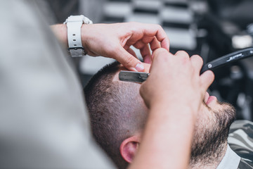 Barber makes an ideal hairstyle. Haircut Fade. Hairdresser performs a dangerous razor .