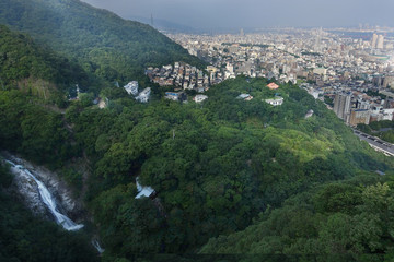 Fototapeta na wymiar Birdeye view of Kobe cityscape , mountain,forest and Nunobiki waterfall from ropewape to mount Rokko in Kobe,Hyogo,Japan