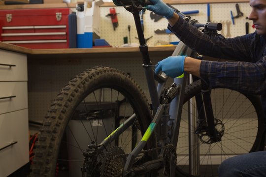 Man adjusting bicycle seat with spanner in workshop