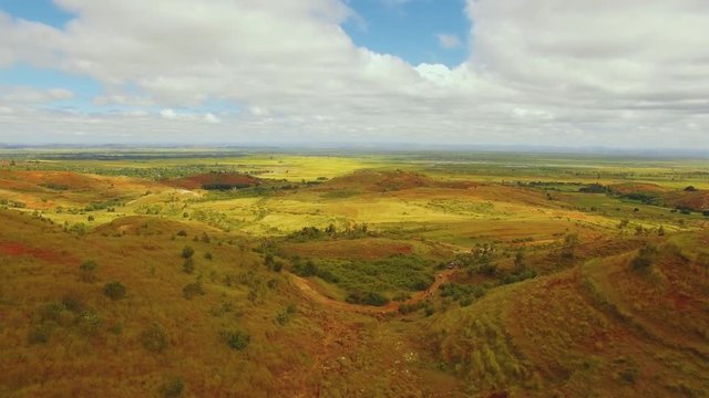 Aerial shot of a landscape in Madagascar with hills, fields and bushes.