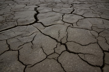 Cracks on the brown earth. The withered earth. The bottom of the parched lake. Background. Texture.