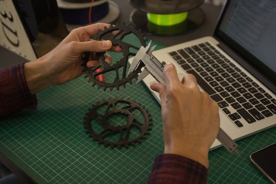Mechanic checking diameter of chain ring with vernier calipers