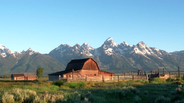 a sunrise wide panning shot of a mormon row barn and grand teton mountain in grand teton national park in the united states of america
