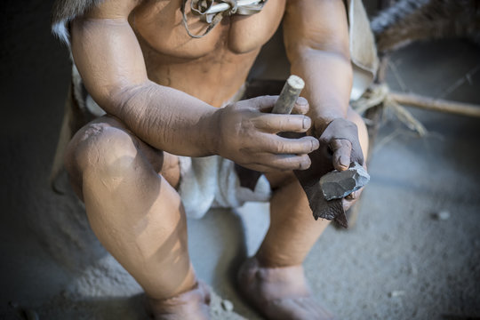 Life-sized sculpture of prehistoric man creating lithic tool