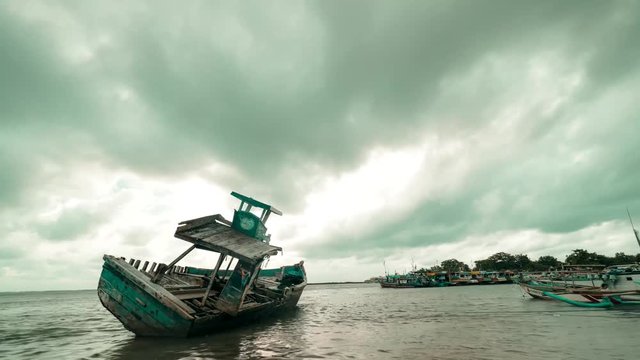 Time lapse footage of abandoned traditional fishing boat on the beach with mobing clouds. Shot in 4k resolution