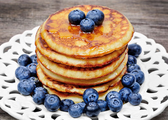 Stacked of pancakes with blueberries in a plate on table