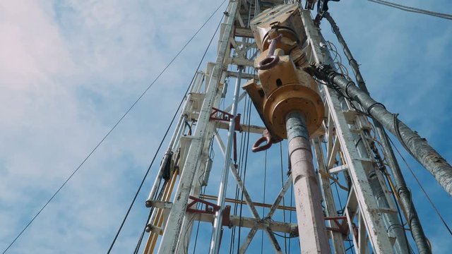 Top Drive System (TDS) Spinning for Oil Drilling Rig at blue sky - Oil and Gas Industry.