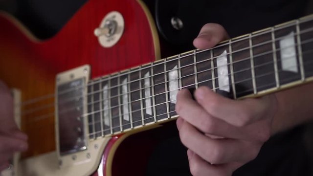 Slo-motion shot of a man quickly picking through a solo on a Les Paul style guitar