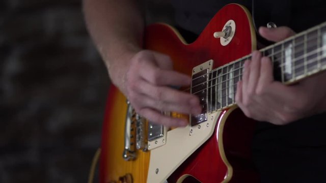 Man playing a guitar points to the humbucker in his guitar