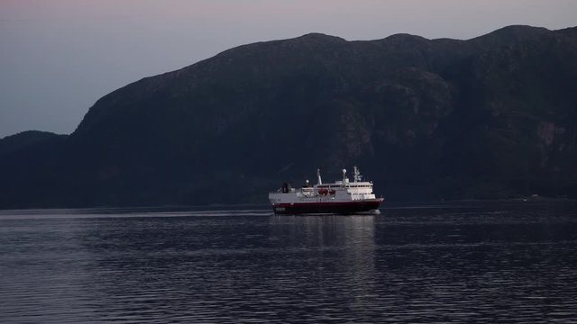 Big ferry sailing over ocean with mountain background.