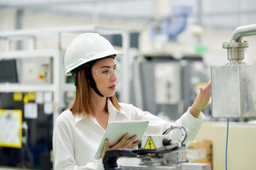 Asian girl engineer wearing a safety helmet and a white safety helmet.while working with a laptop...