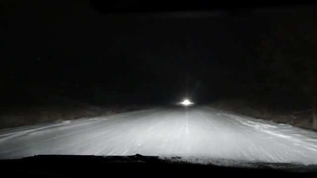 Night driving in the car in the snowfall blizzard on the snow-covered road.  Low beam and high beam of headlighs. Road safety. Bad non-flying weather. 