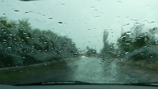 Rainy weather. Driving in a car in heavy rain downpour on a wet road. Raindrops on the windshield