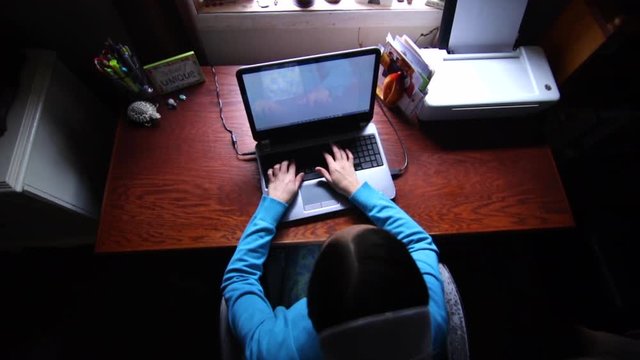 An overhead shot of a Mennonite woman typing on a laptop computer in slow motion.