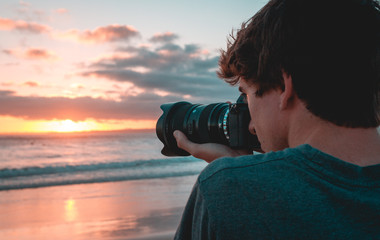 Filmmaker at the beach shooting sunset 