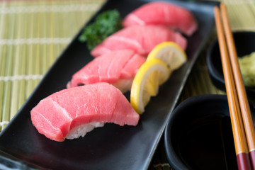 Otoro tuna sushi on black plate along with Japanese sauce and green leaf decoration, Japanese food, close up at sushi ..
