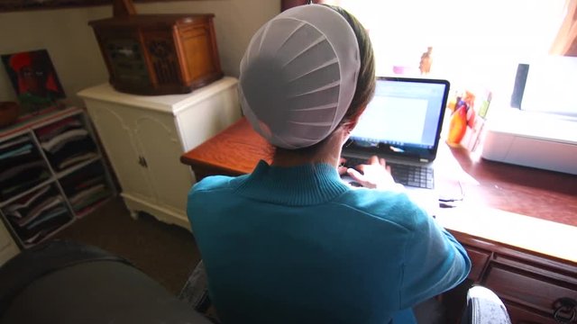 An over the shoulder look at a Mennonite woman working on a computer.