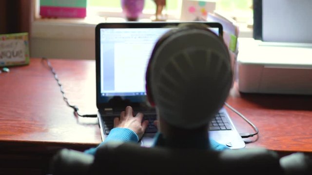 A young Mennonite woman comes into focus typing on a computer.