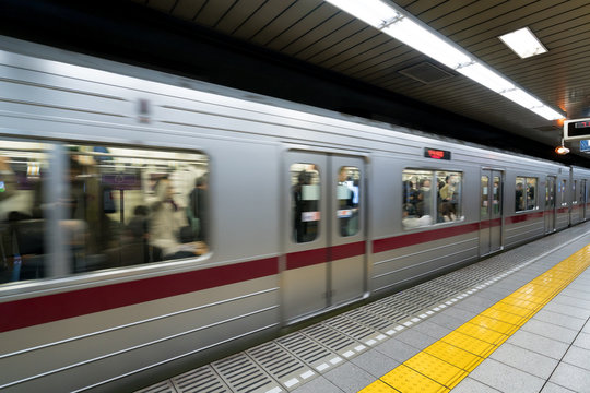 Interior of a Tokyo subway station and platform with subway commuters in Tokyo, Japan.
