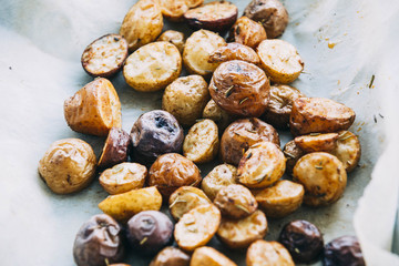 Roasted multicolor creamer potatos on parchment paper. The potato is a starchy, tuberous crop from the perennial nightshade Solanum tuberosum. Slang terms for the potato include tater and spud