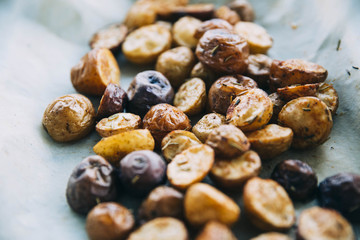 Roasted multicolor creamer potatos on parchment paper. The potato is a starchy, tuberous crop from the perennial nightshade Solanum tuberosum. Slang terms for the potato include tater and spud