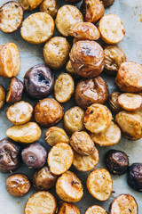 Roasted multicolor creamer potatos on parchment paper. The potato is a starchy, tuberous crop from the perennial nightshade Solanum tuberosum. Slang terms for the potato include tater and spud