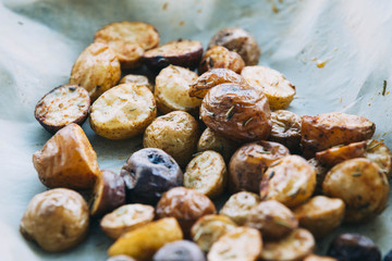 Roasted multicolor creamer potatos on parchment paper. The potato is a starchy, tuberous crop from the perennial nightshade Solanum tuberosum. Slang terms for the potato include tater and spud