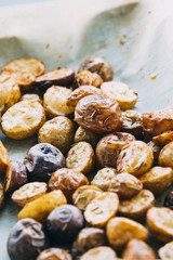 Roasted multicolor creamer potatos on parchment paper. The potato is a starchy, tuberous crop from...