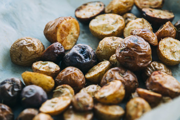 Roasted multicolor creamer potatos on parchment paper. The potato is a starchy, tuberous crop from the perennial nightshade Solanum tuberosum. Slang terms for the potato include tater and spud