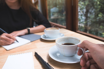 Closeup image of two businessman drinking coffee while talking and meeting in office
