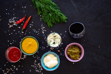 Different dip sauce in bowls near chili pepper and greenery. Ketchup, mayonnaise, mustard, soy...
