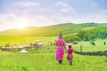 Mother and daughter wearing Mongolian costumes on the grassland