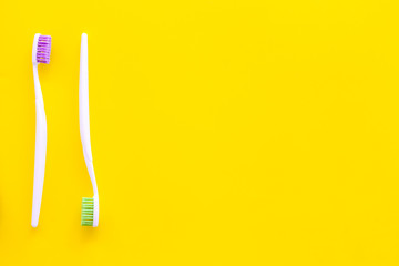 Oral hygeine. Toothbrushes on yellow background top view copy space