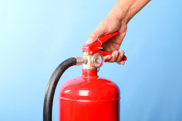 Hand holding fire extinguisher on blue background.